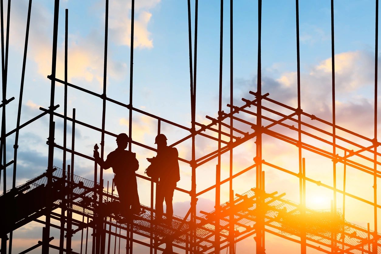 Silhouette of workers on scaffolding at sunset