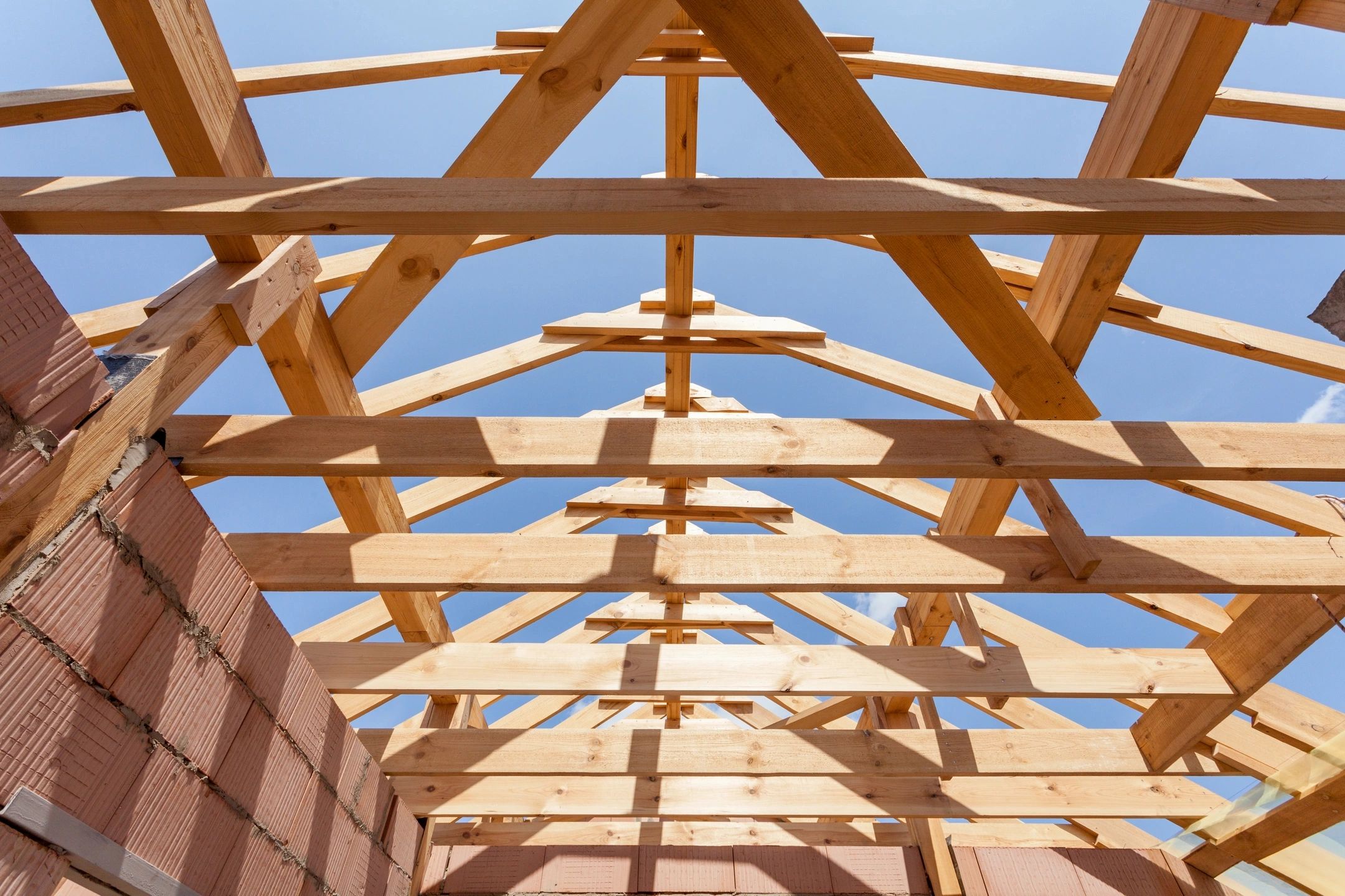 Wooden roof framing trusses against blue sky