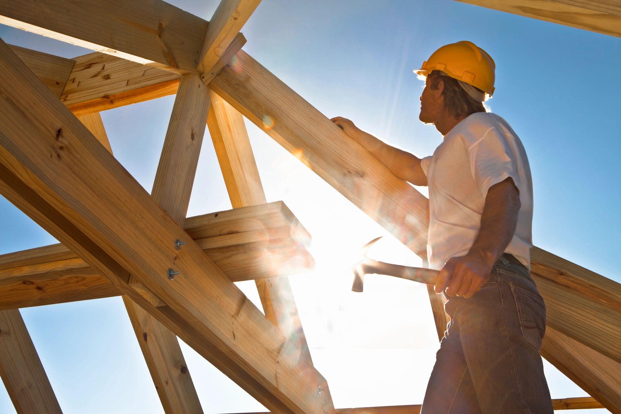 Construction worker on roof framing in sunlight
